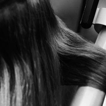 Close up of a model having a section of her hair curled with tongs.